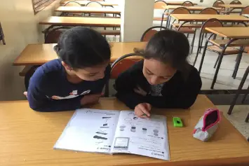 Deux élèves travaillent ensemble sur un cahier dans une salle de classe