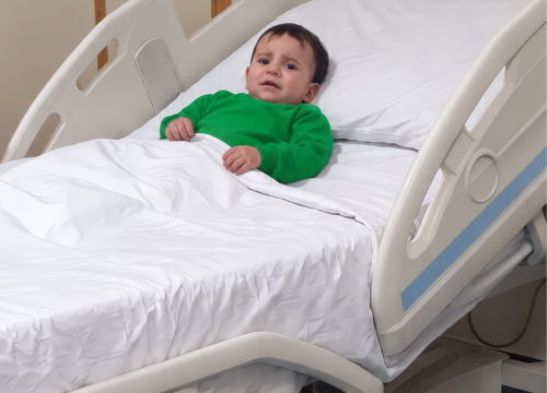 Soleiman portant un pull vert dans un lit médical.